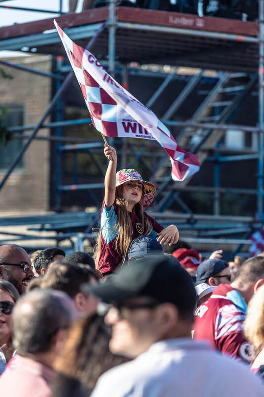 a girl waving a flag wearing a west ham football shirtcelebrating winning the europa cup