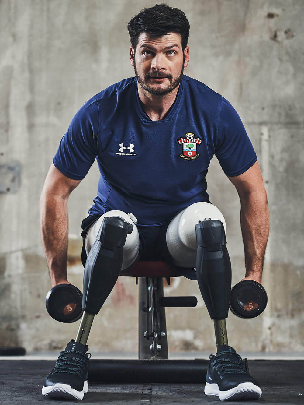 paralympian athlete excersising with dumbells, wearing a blue southampton fc tee shirt